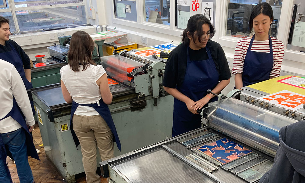 participants letterpress printing across two presses from woodblocks that were generated by code.