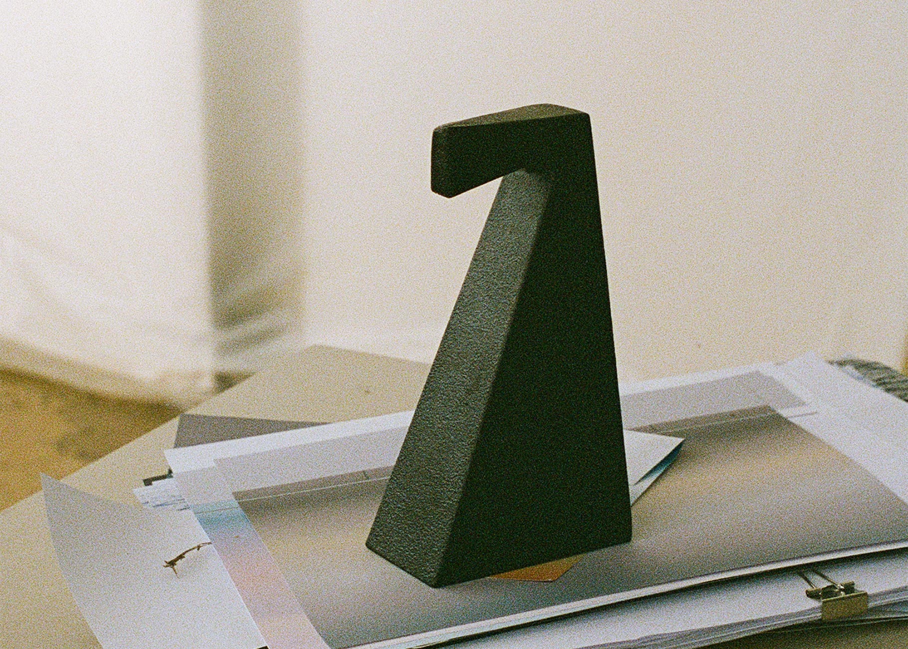 A Laguz cast iron bookend resting on papers, showing its textured surface and angular form.