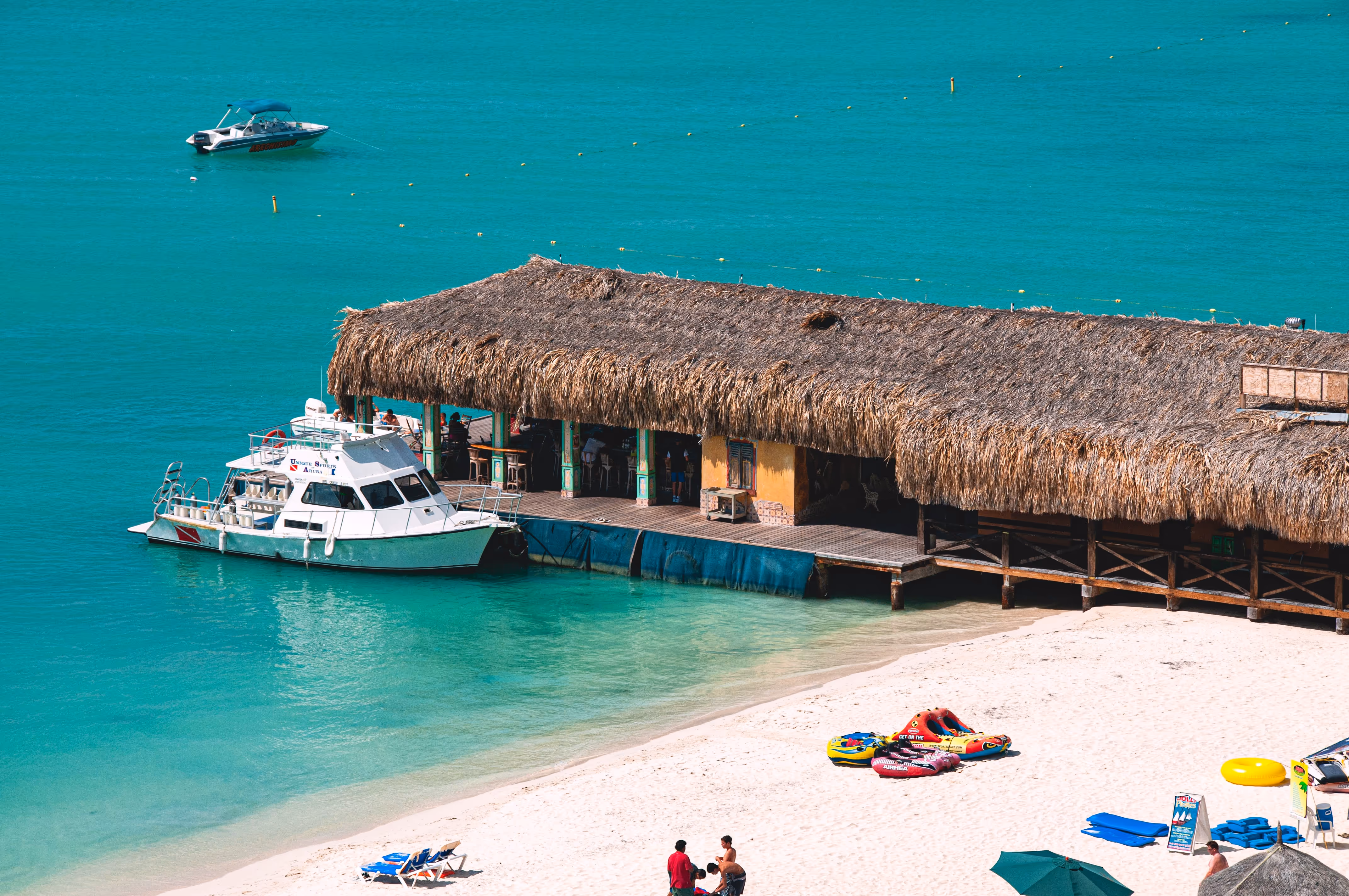 House with straw roof stretching out onto a turquoise blue sea