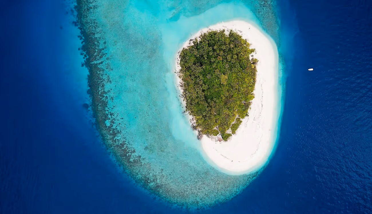 Island with greenish blue water and a boat approaching