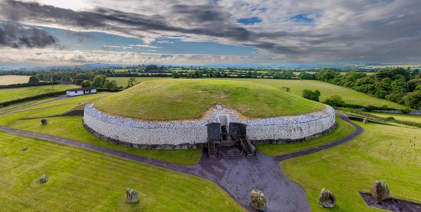 Newgrange Passage Tomb with cloudy skies and green fields