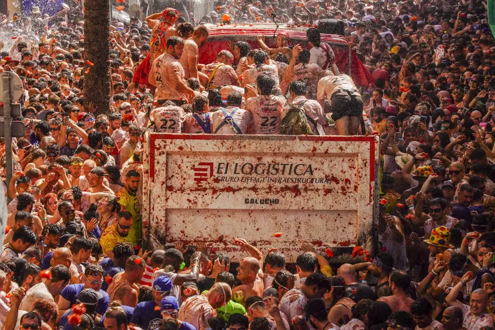 Large crowd around lorry full of people during La Tomatina