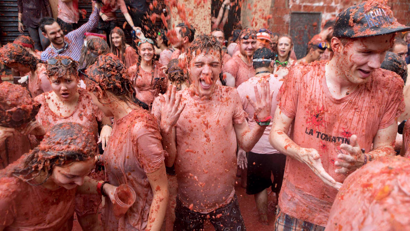 Group of people in stained tshirts covered in crushed tomatoes