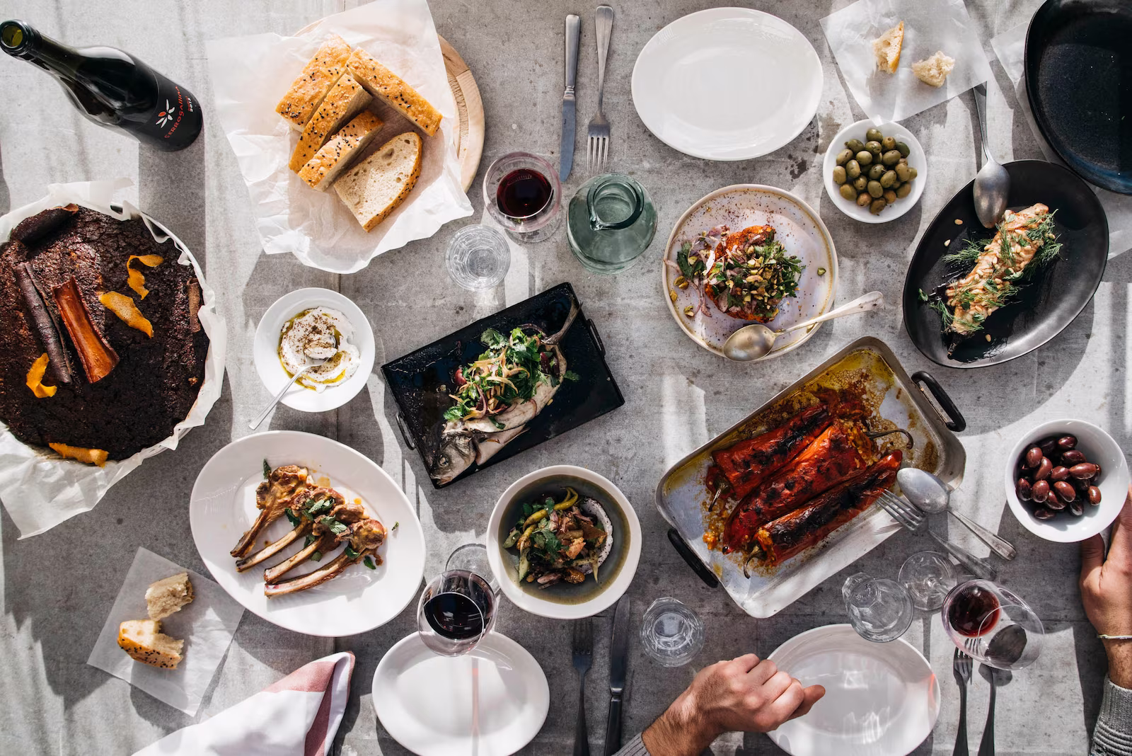An array of dishes and Valencian Cuisine with wine, plates, forks and spoons on table