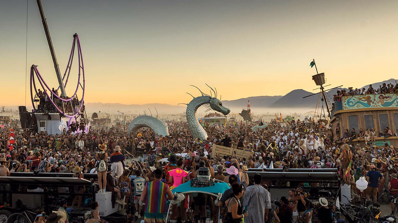 Large crowd watching metal art installations at Burning Man