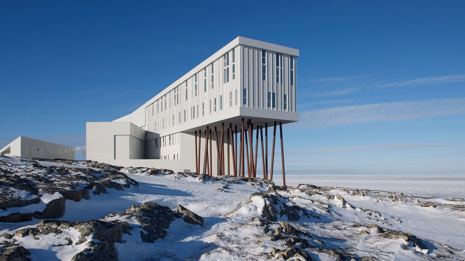 Fogo Island Inn on edge of island with blue skies and snow