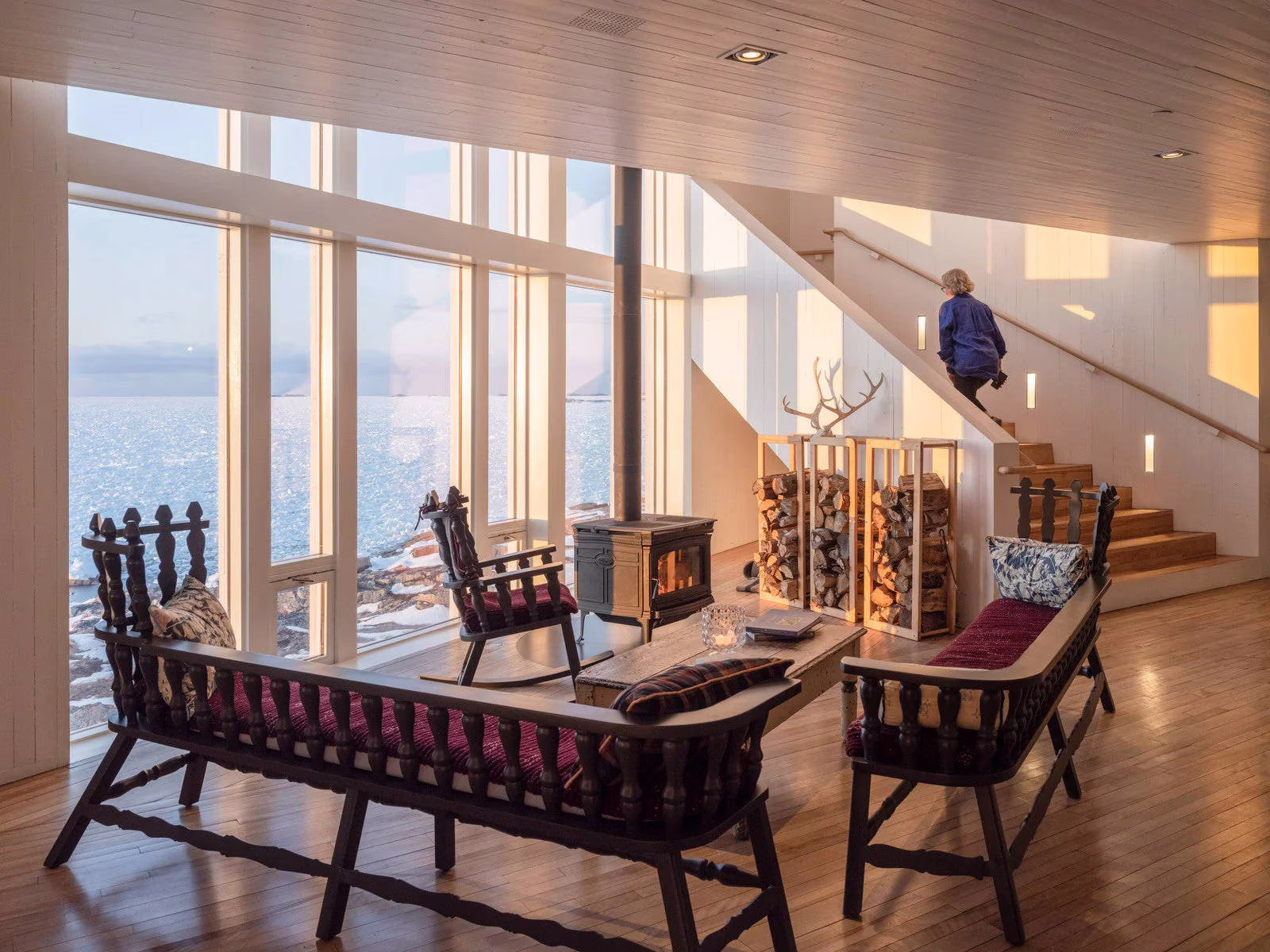 Woman walking up stairs in cosy room with scenic ocean view outside window