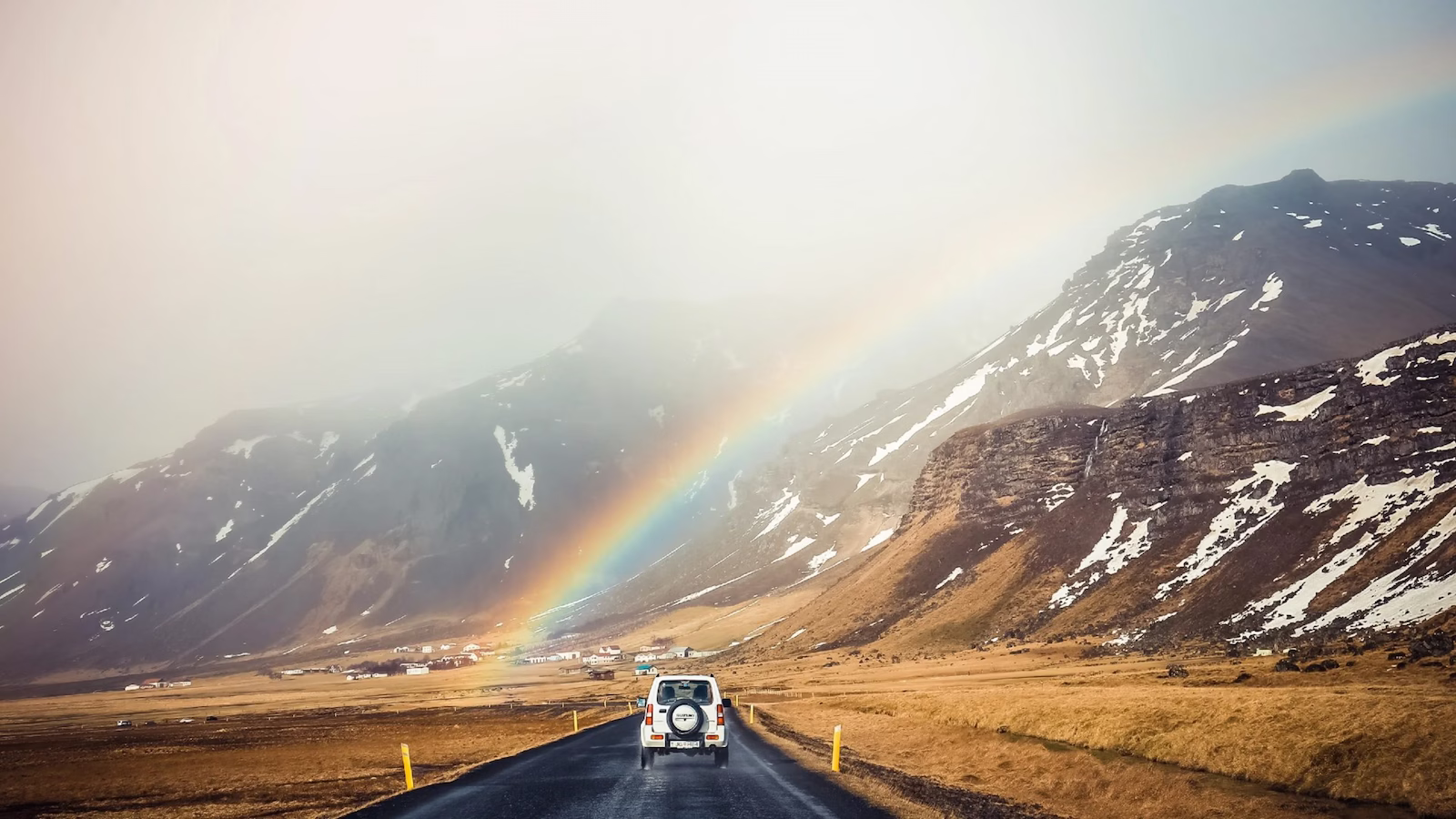 4x4 car driving on road in fog with rainbow and mountains