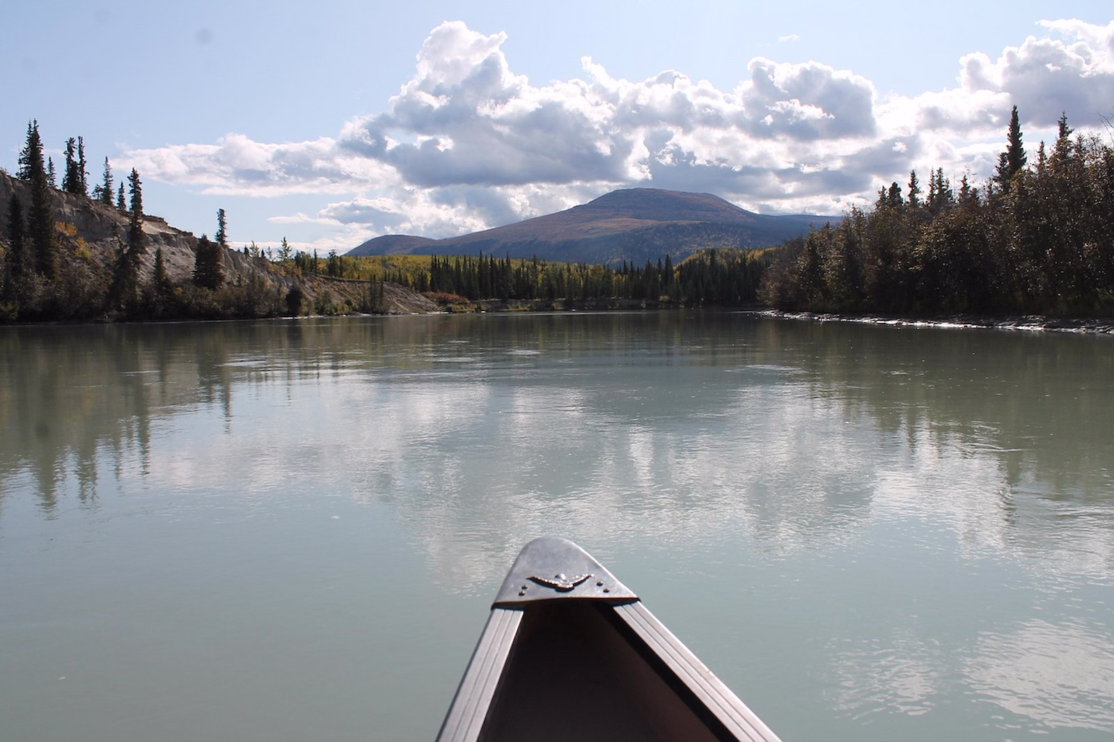 view from inside canoe overlooking lake surrounded by forest and hills in the distance
