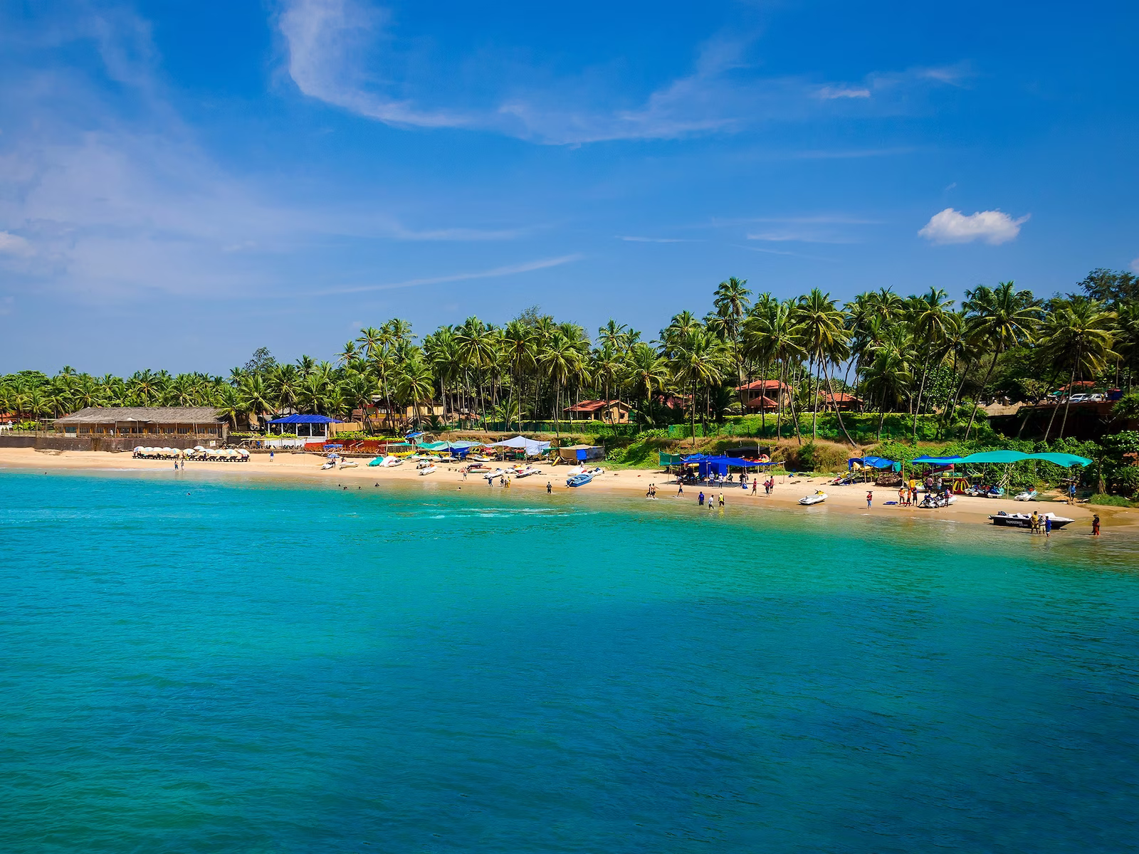 beach in Goa with colourful houses on seaside and palm trees