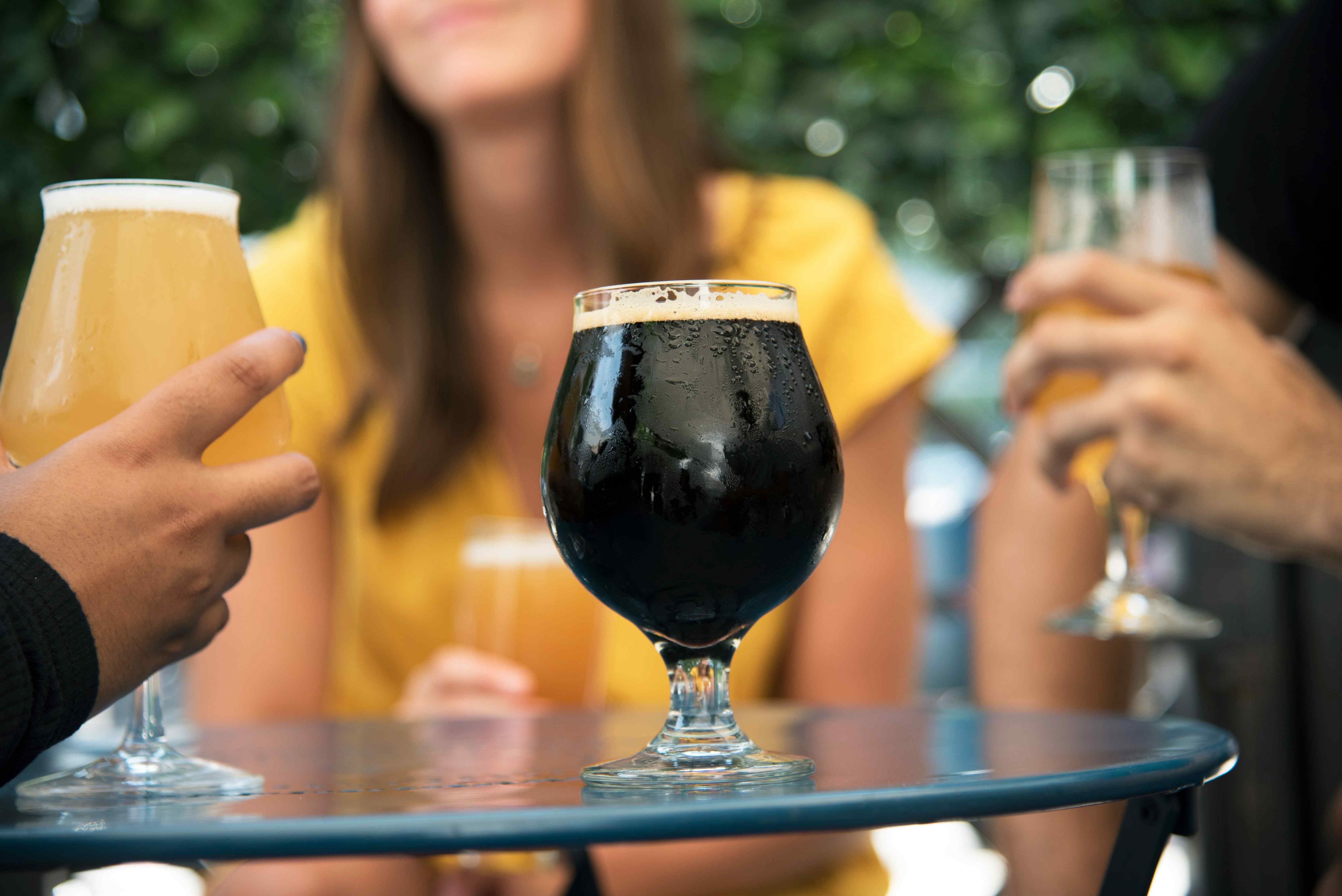 Pint of dark beer and people holding other drinks