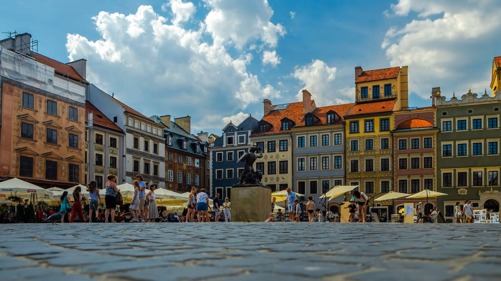 Colourful buildings in city square with people walking through