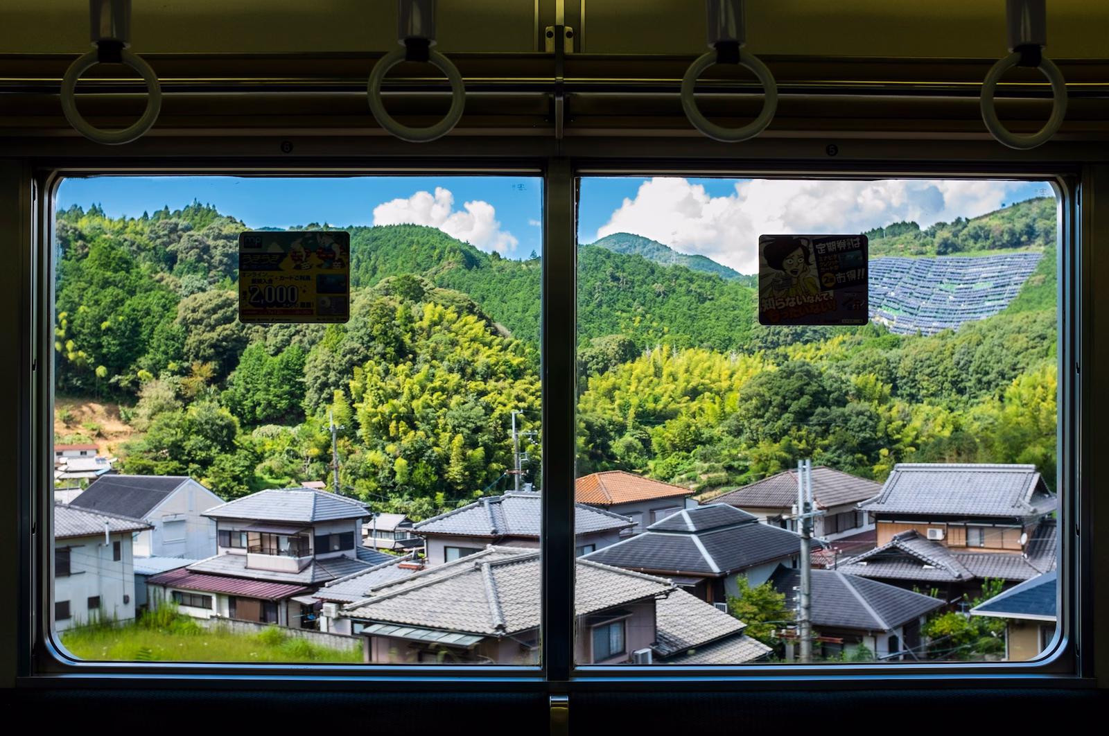 view out of the train in japan with hills houses and solar panels