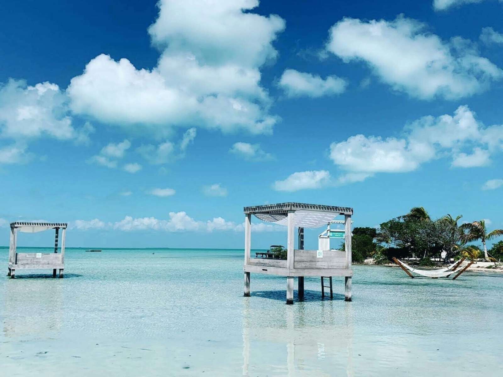 Beach huts on clear blue water with cloudy bright sky