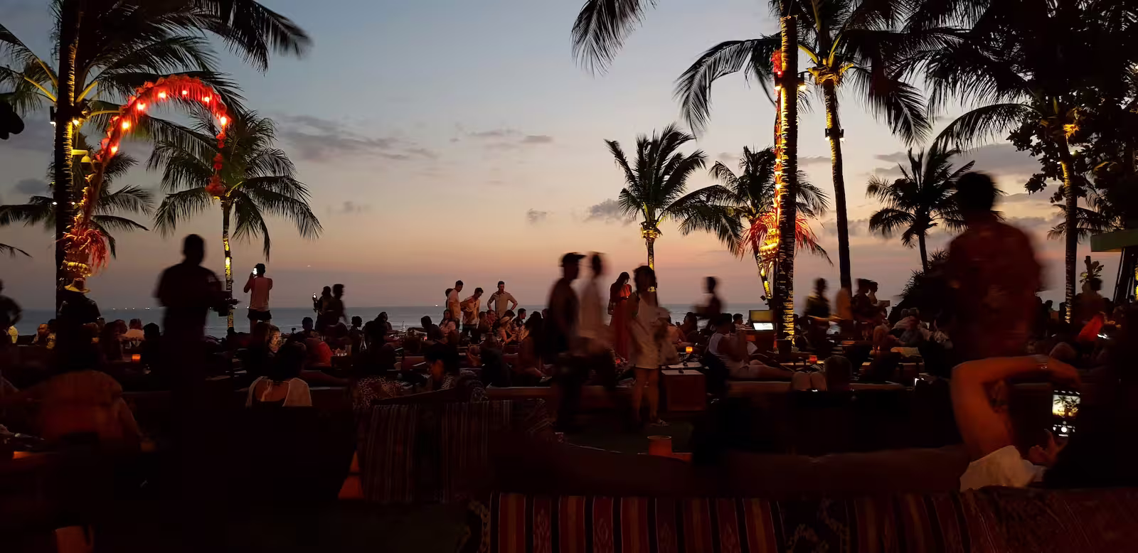 People on a beach at sunset with palm trees