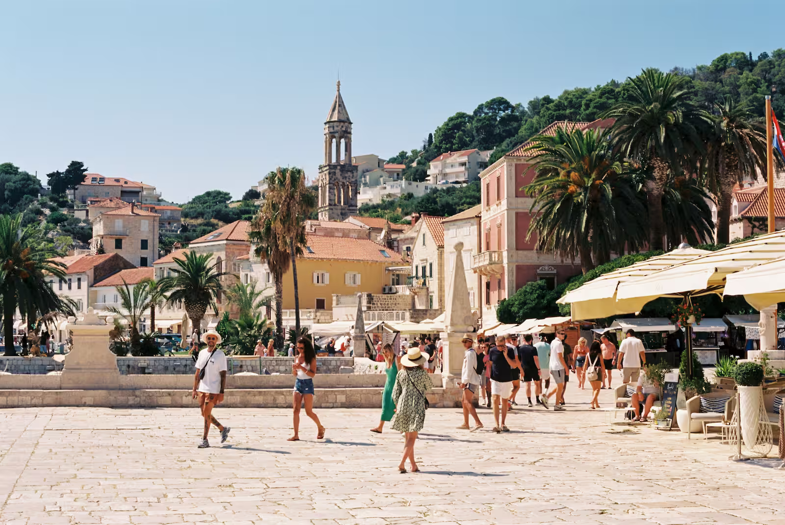 Croatian town square with people and green palm trees