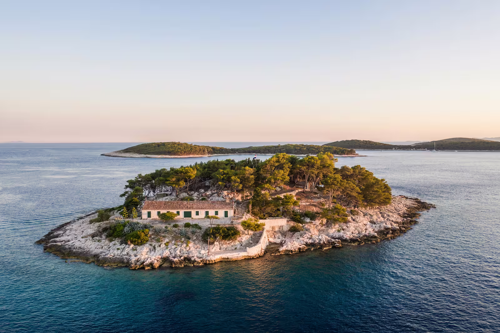 Small Croatian island surrounded by ocean with islands in background