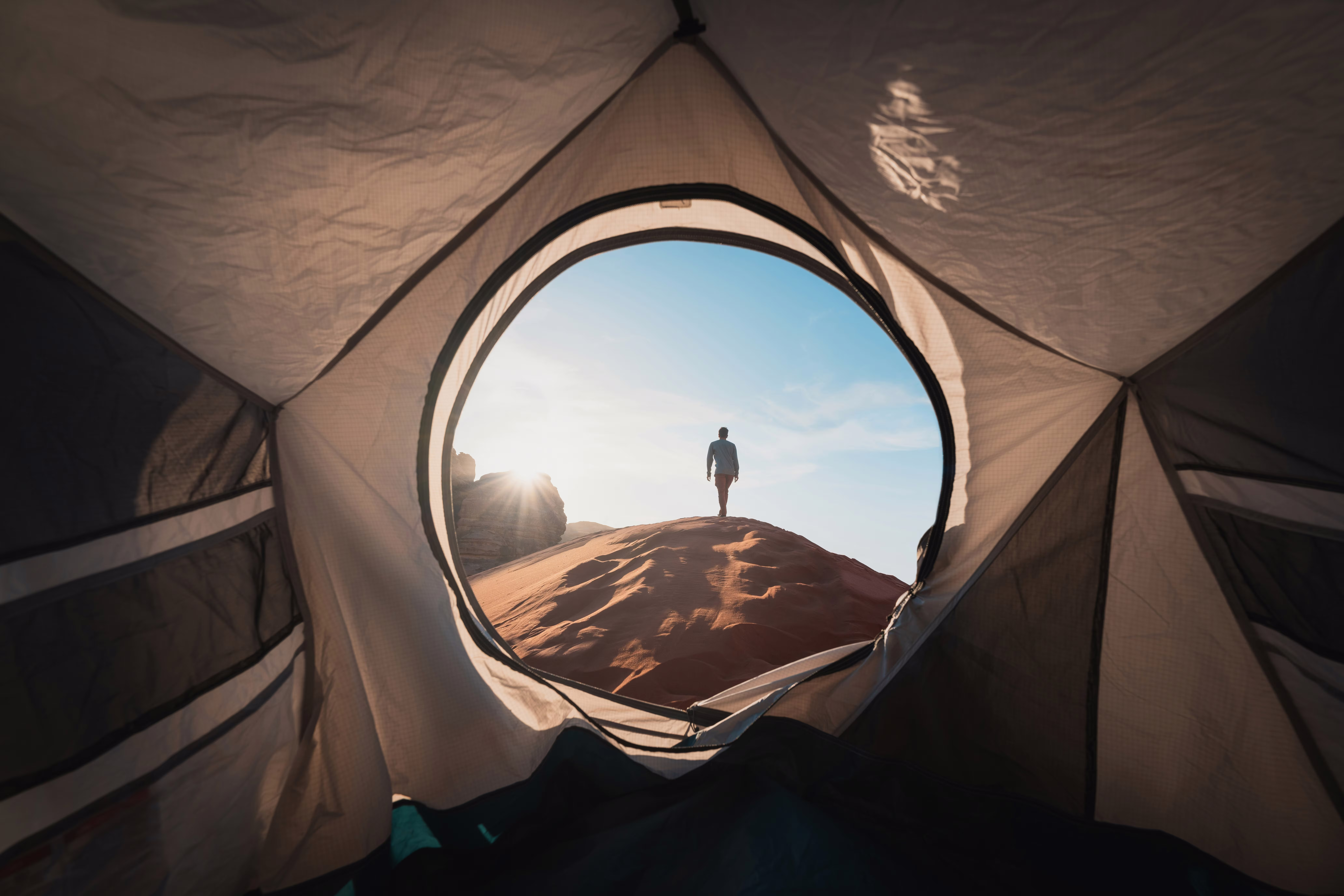 view from inside a tent with sand and person outside