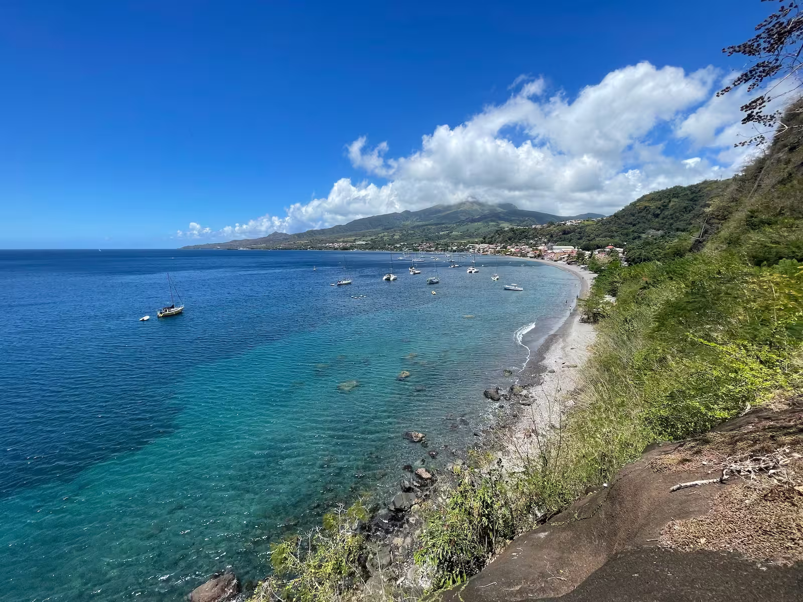 Bay with boats against beach and green hills