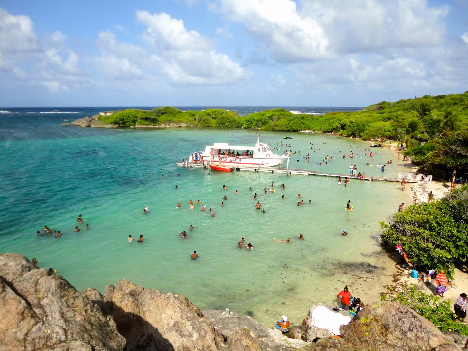 Docked ferry on beach with people in ocean