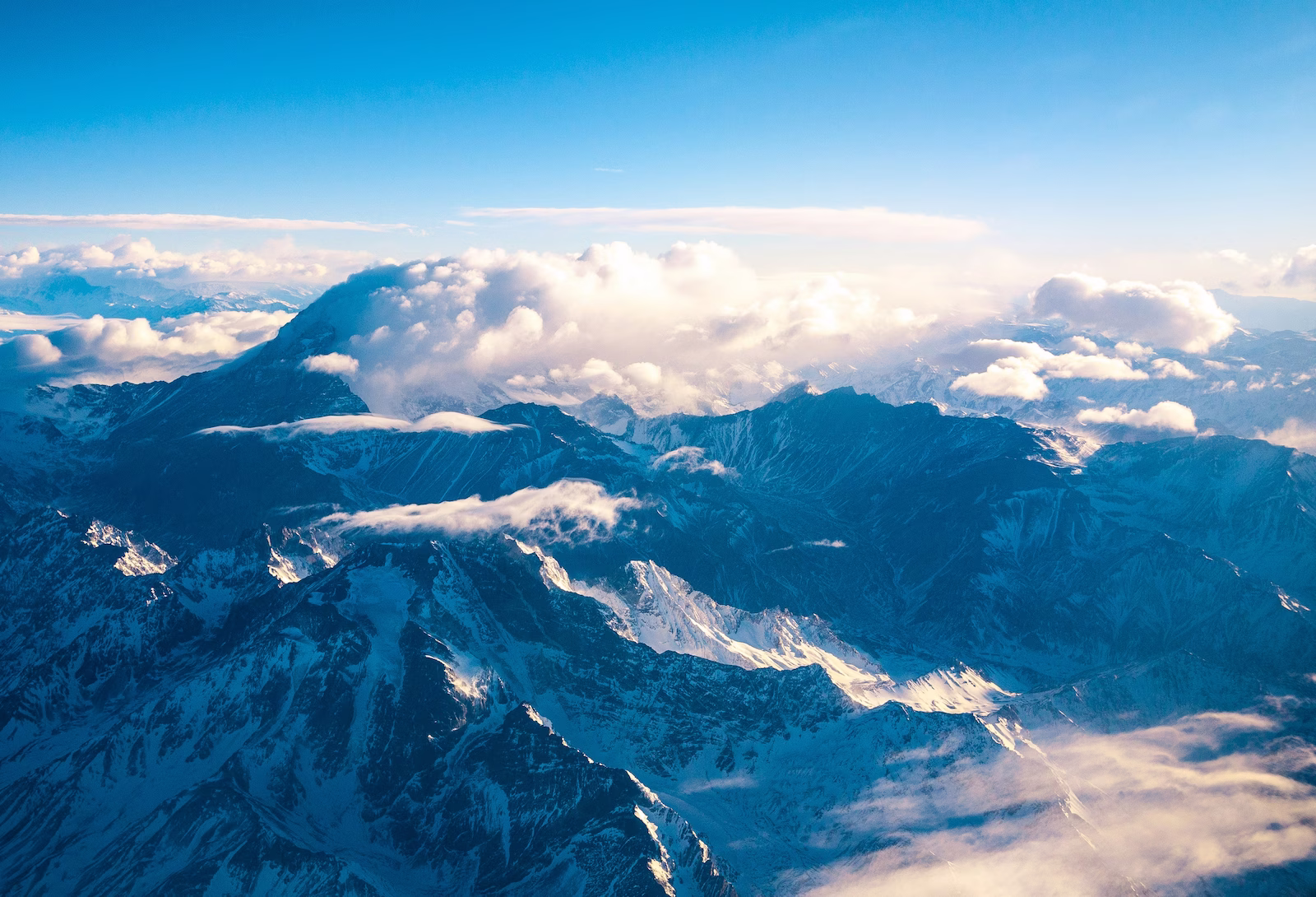 aerial view with clouds over a mountain range with snow