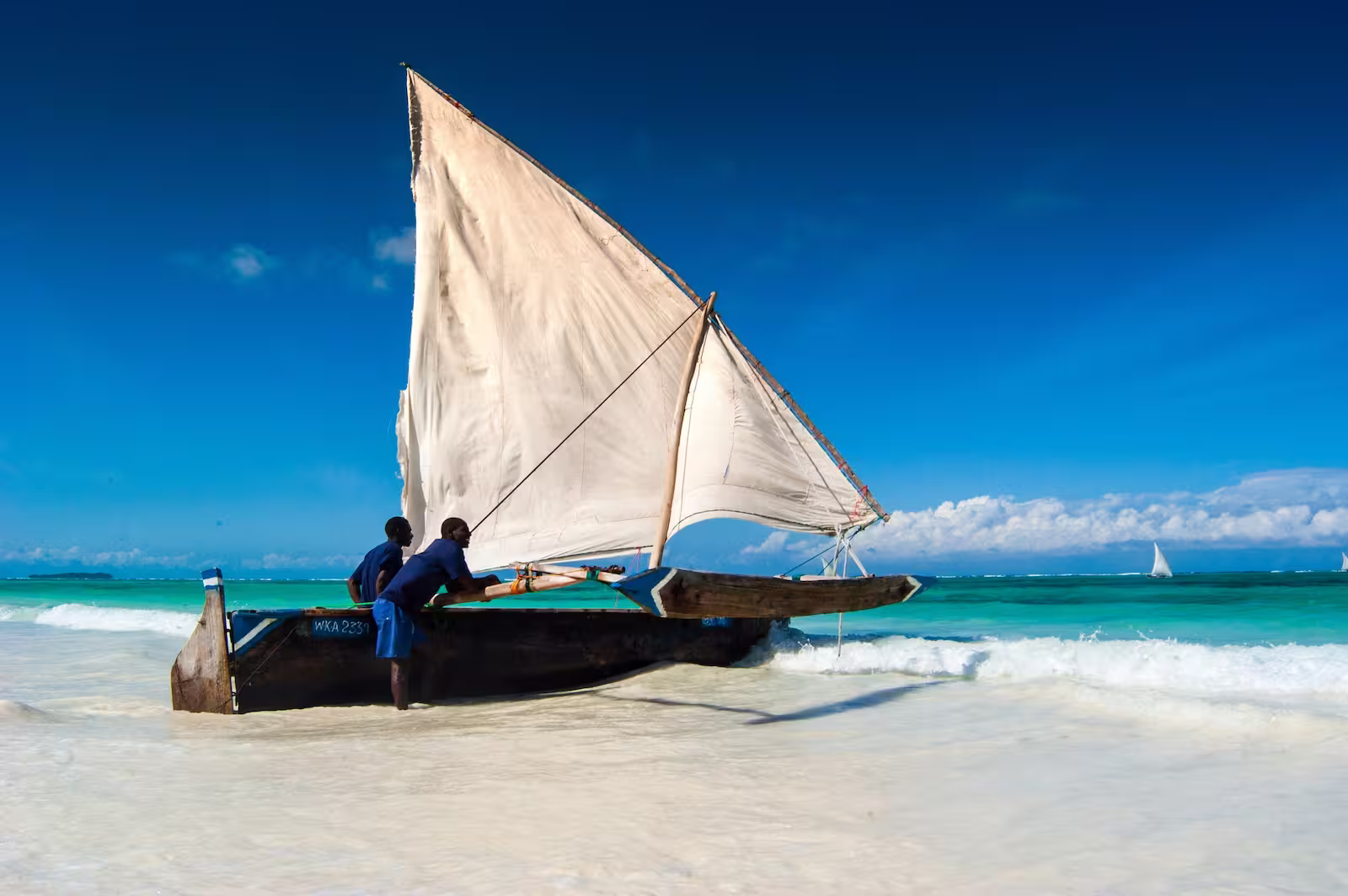 Two men pushing small boat into ocean