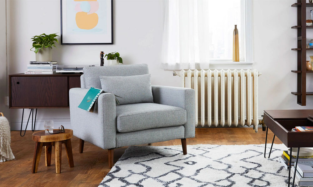 Grey Armchair with a grey cushion and a book on it. It is placed in a cozy living room