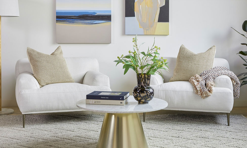 Two chairs with white upholstery in a living room with a coffee table creating a cozy reading nook