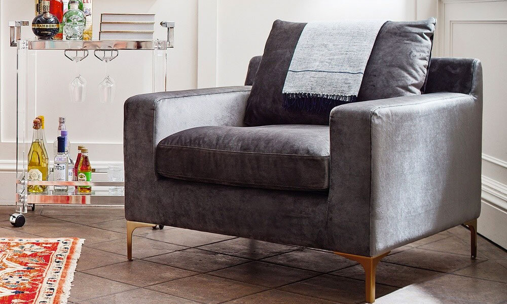 Grey accent chair with metal legs in a cozy nook near a small bar