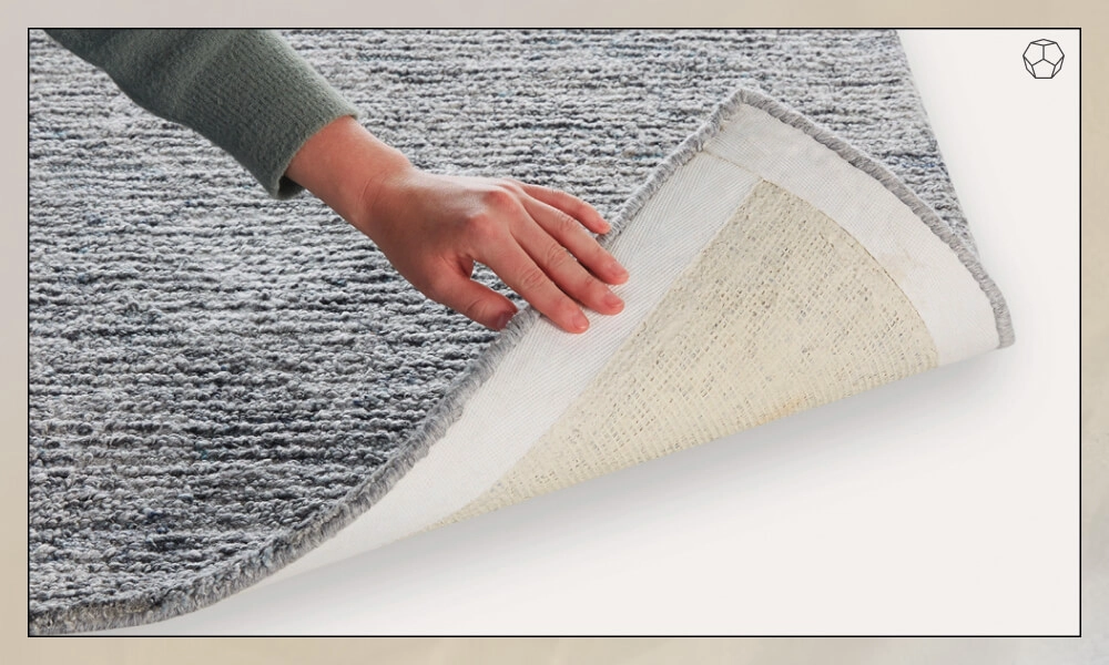 Man holding the corner of a grey rug