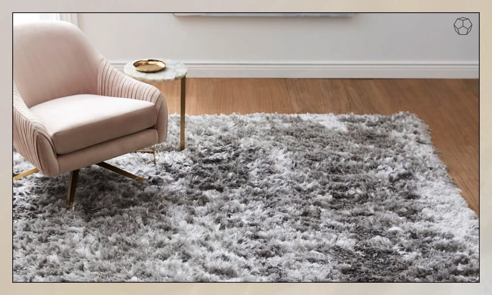 Grey soft area rug placed under one pink accent chair and a small side table