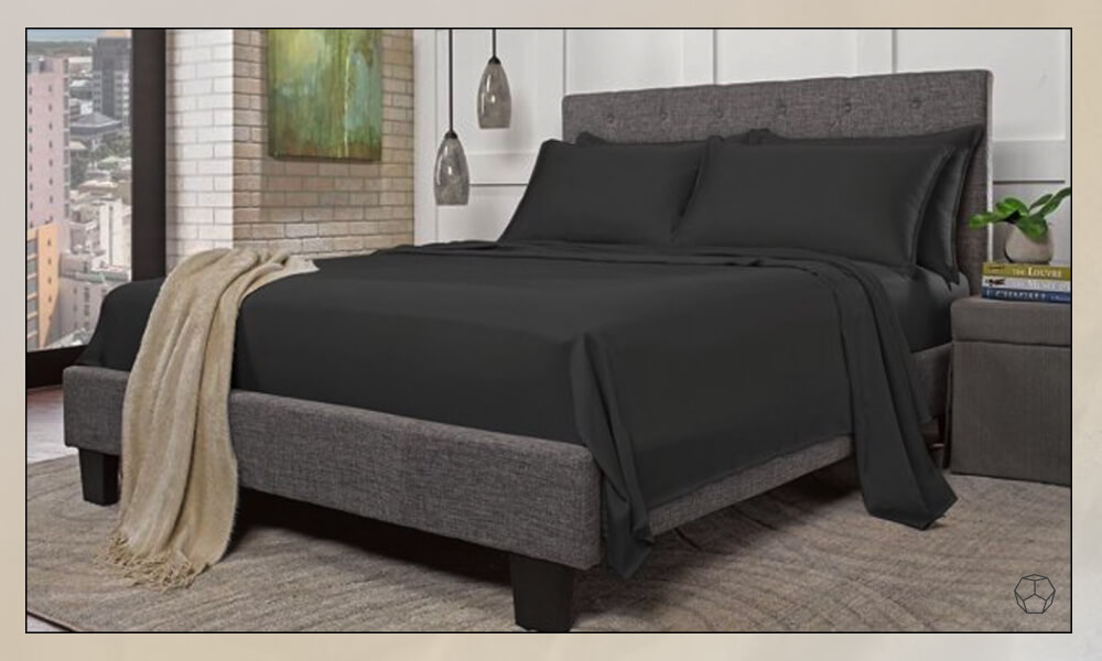 Black sheets in a grey matress with a grey upholstered bedframe