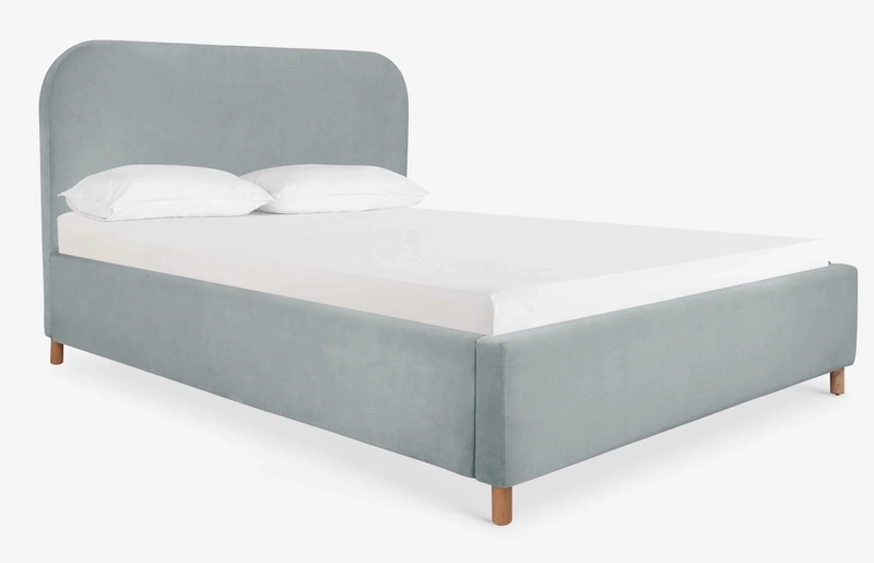 Dove velvet upholstered bed frame with a round corners headboard and a mattress with white sheets