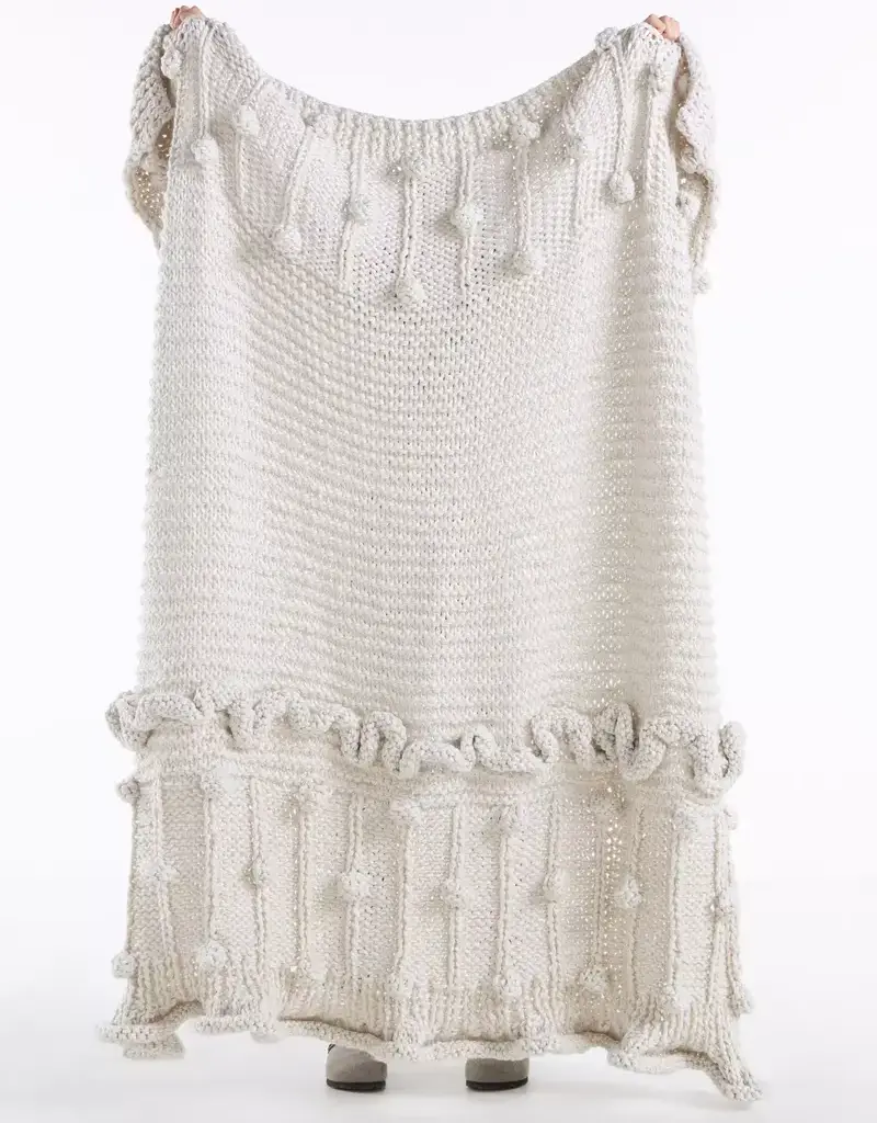 Person holding a white knit throw blanket