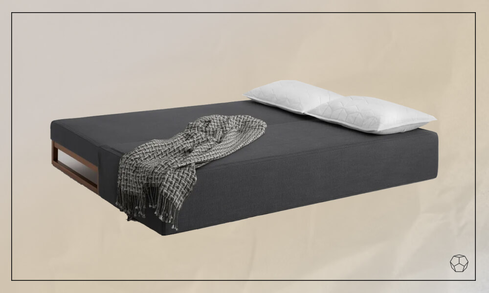 Uncovered sleeper sofa in the floow with white pillows and a patterned throw blanket