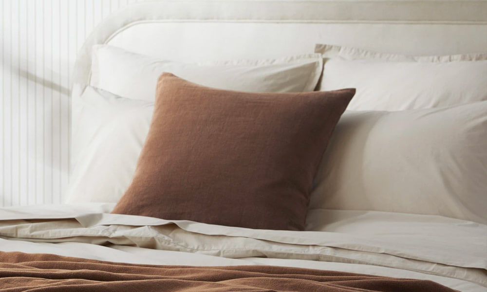 Brown Linen Pillow matching a group of white bed pillows