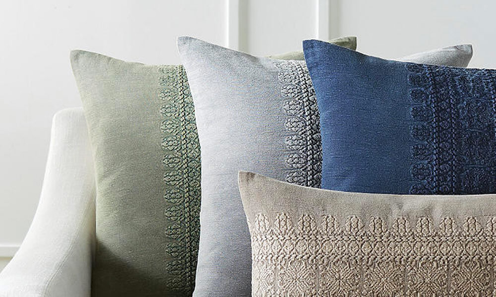 Four stonewashed and textured decorative pillows in a white couch