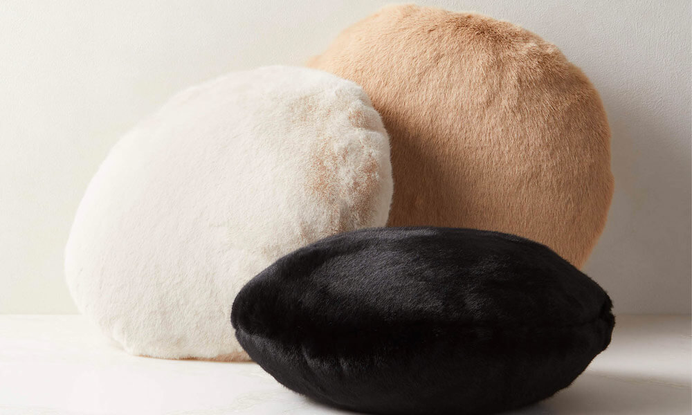 three Rounded Throw Pillows. They are black, brown and white.