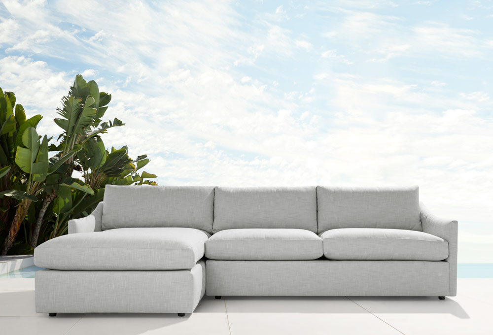 Light gray Outdoor Sectional with a modern design placed outdoors near plants and under a cloudy sky