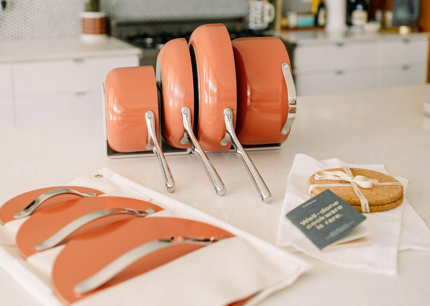 Peach colored caraway cookware set stored in a white kitchen