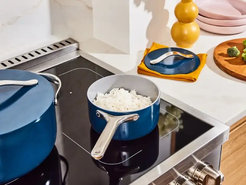 Blue saucepan with rice on an electric stovetop, next to a matching blue spot