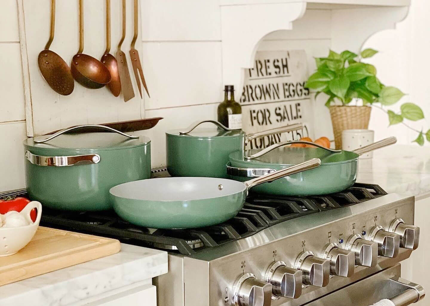 Caraway green cookware ceramic set in a stove placed in a white kitchen