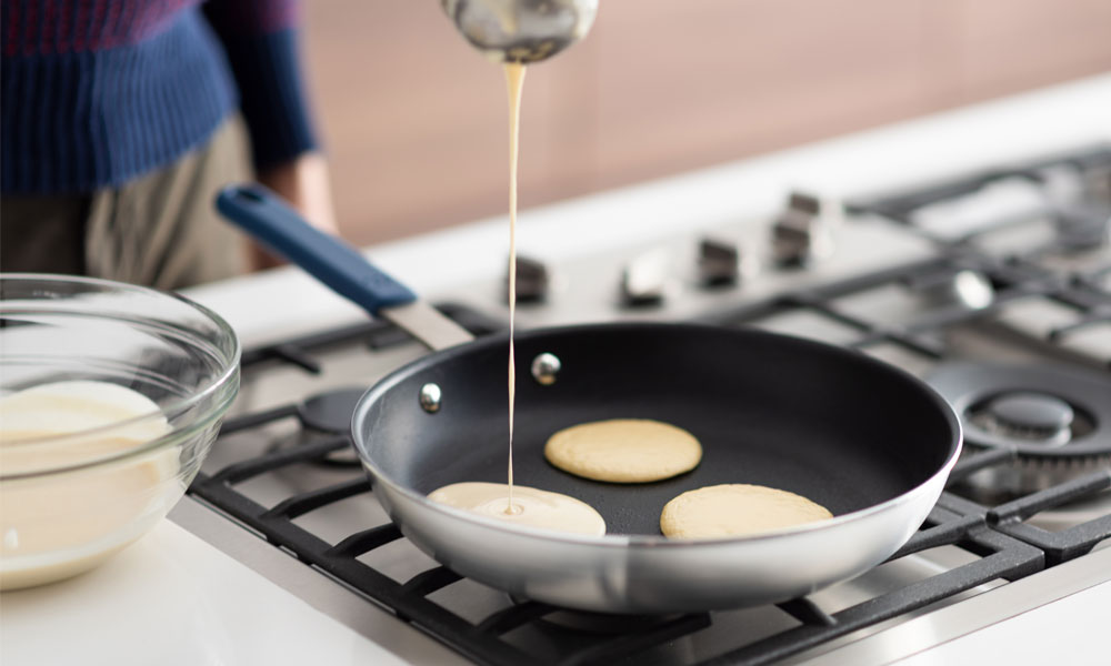 a person pours pancake batter onto a hot pan, creating fluffy pancakes that sizzles 