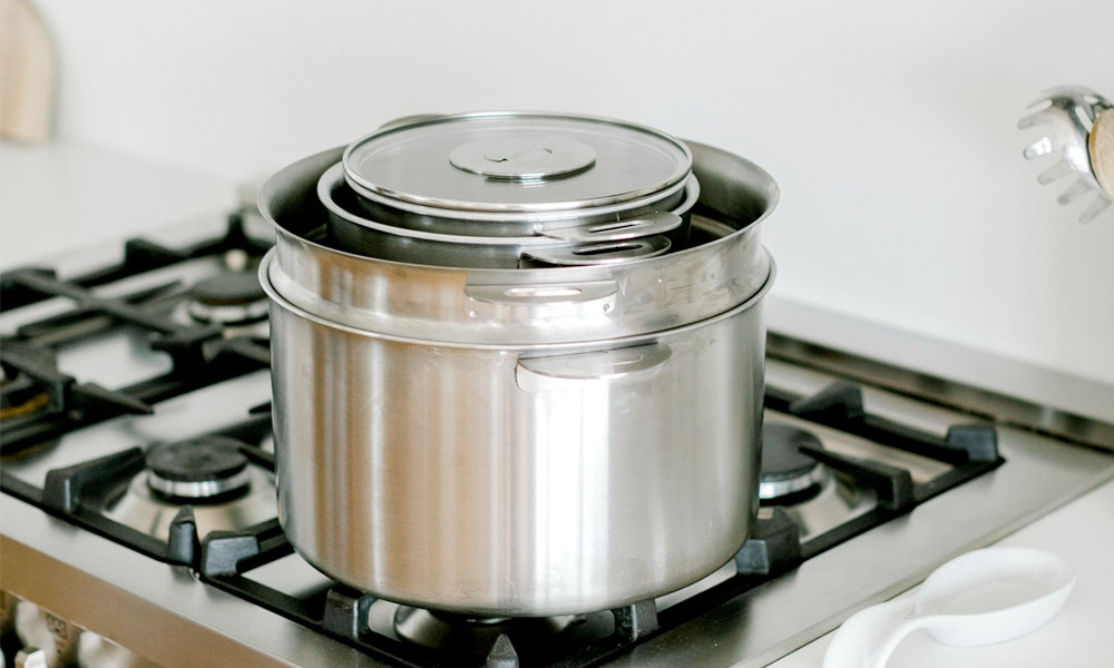 Stainless steel pots stacked positioned on a gas stove in a kitchen