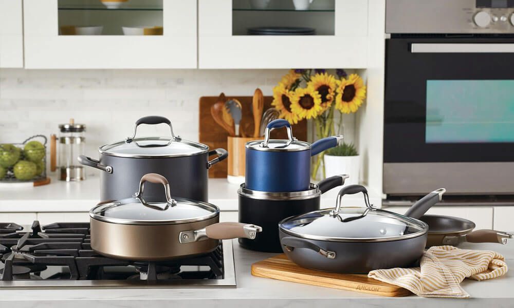 Cookware set with pots and pans in black, grey, and blue in a kitchen