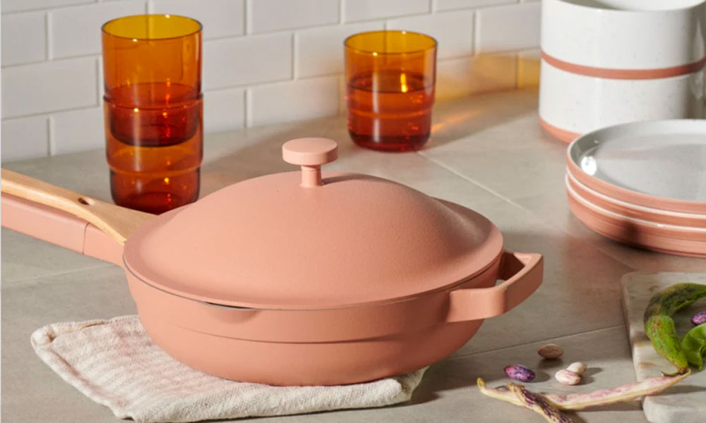 A light peach pan with a glass lid and a wooden handle