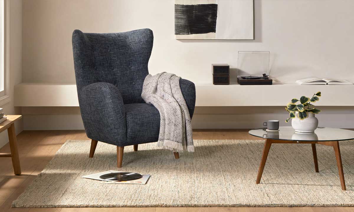 Grey wingback chair with wooden legs in a cozy living room