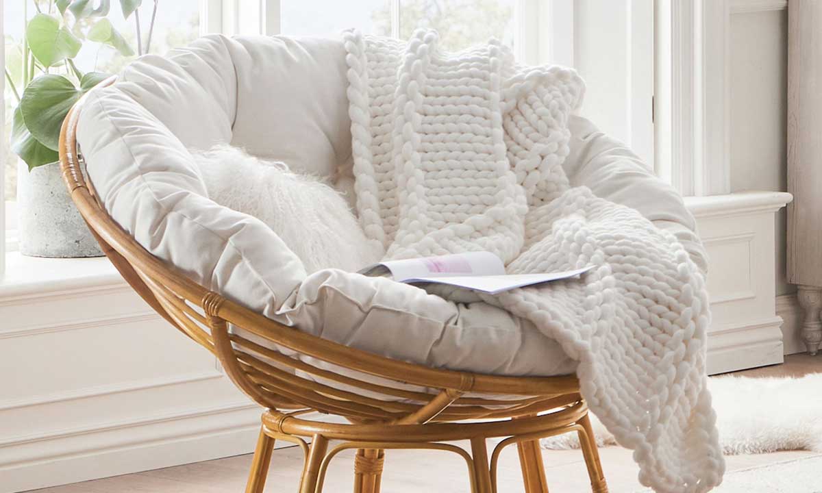 Papasan Chair with a white rounded cushion and a white woven throw blanket