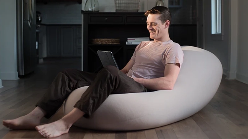Man sitted in a bean bag working on his computer