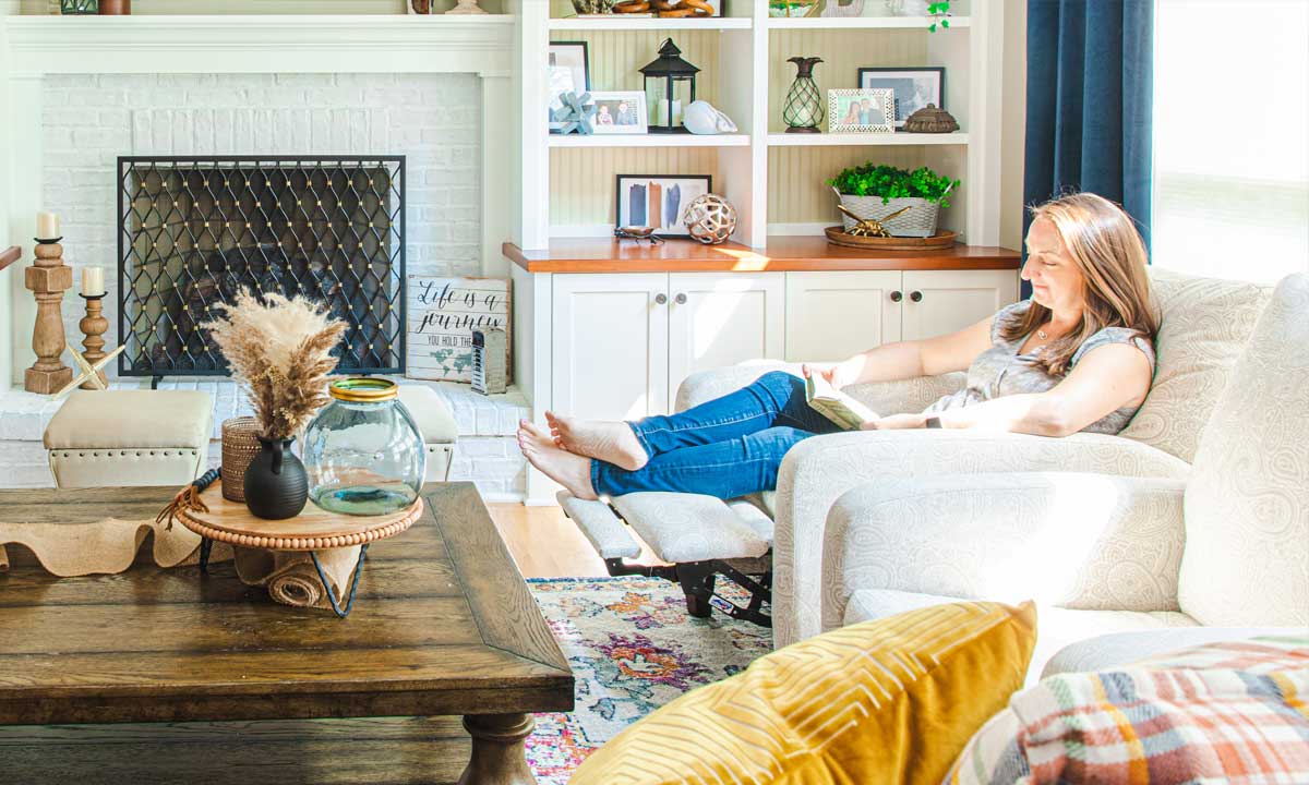 Woman sitted in a recliner chair reading a book in a bright living room